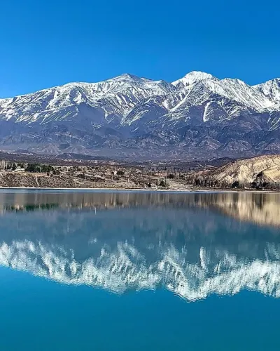 Vista panorámica del Dique Potrerillos en Mendoza, con su agua turquesa y las montañas de la cordillera de fondo.